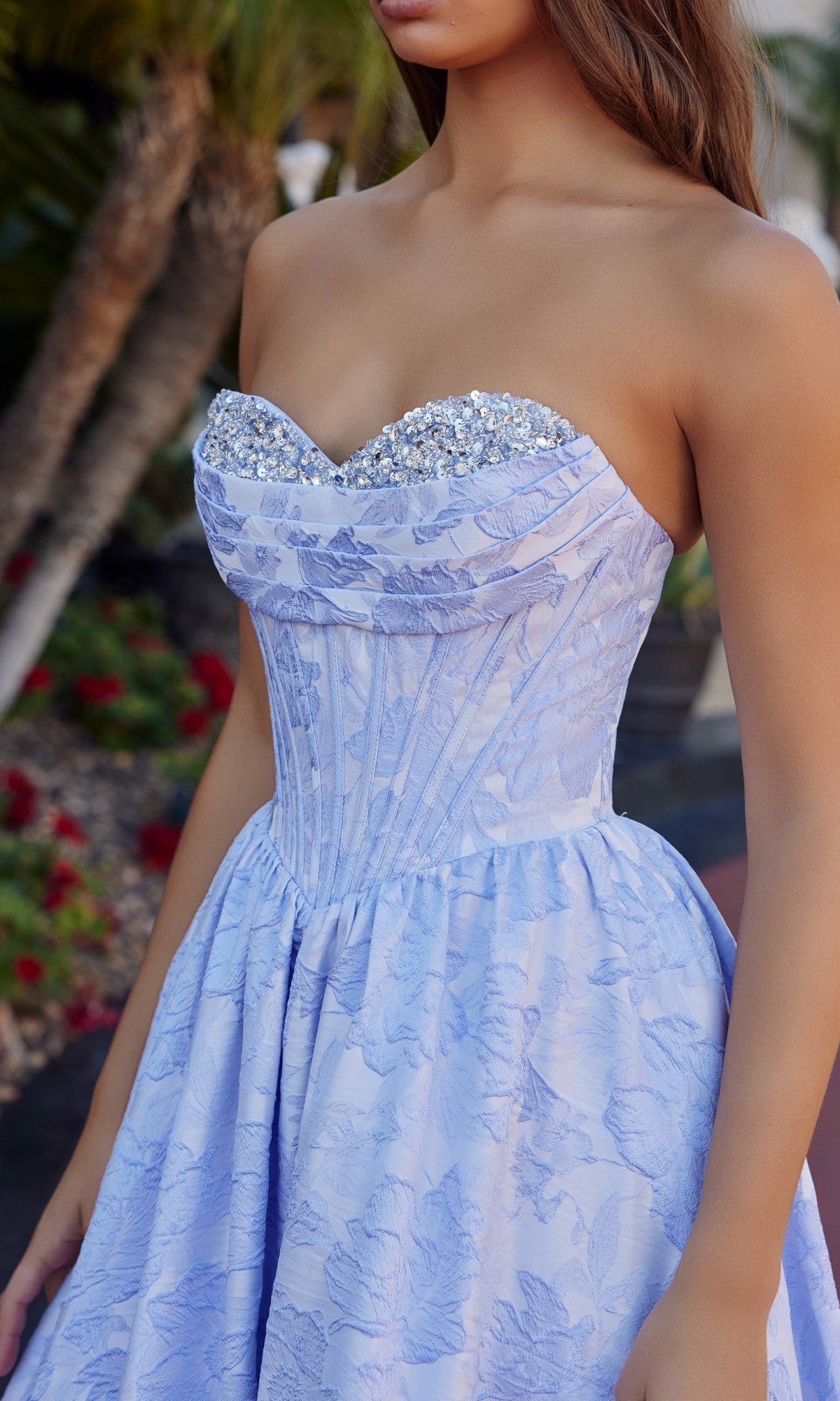 A woman in the Nox Anabel T1912 long prom dress, a light blue floral jacquard gown with a strapless fitted bodice and sparkling jeweled sweetheart neckline.